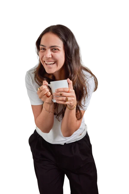 Nikki is wearing a white t-shirt, orange cardigan and beige trousers as she looks down at her smartphone.